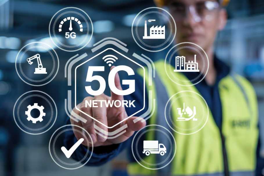 Unscharfes Bild eines Fabrikarbeiters mit gelber Weste im Hintergrund, der ein 5G-Symbol berührt, das im Vordergrund schwebt.