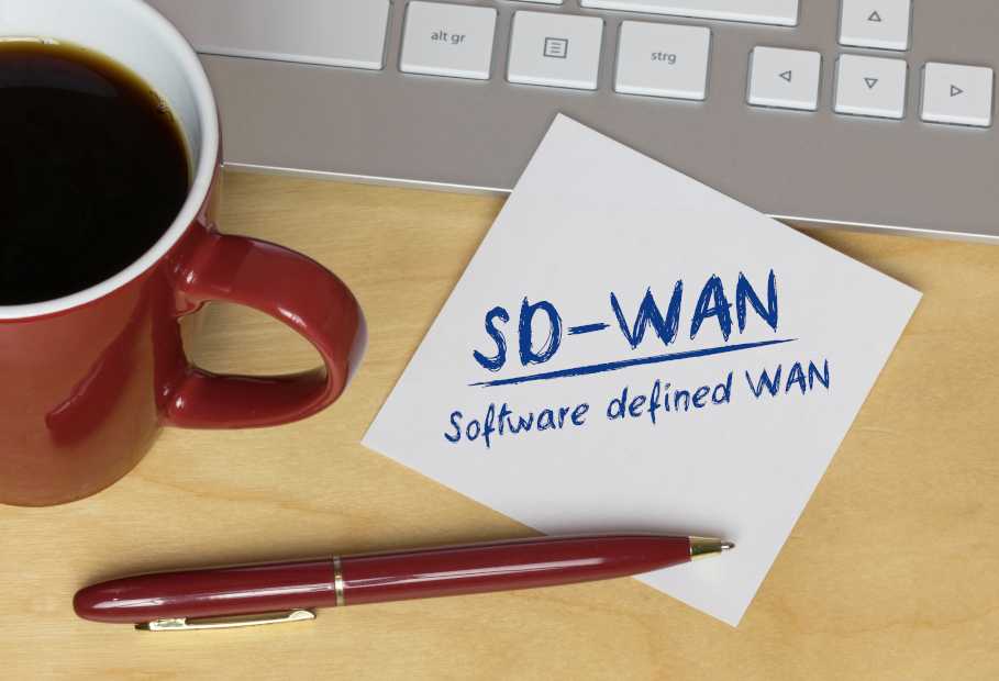 Handschriftliche Notiz „SD-WAN“ neben einer Tastatur und einer Tasse Kaffee