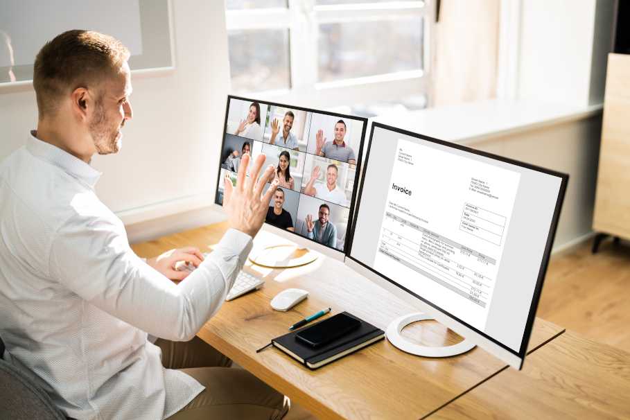 Mann am Schreibtisch vor 2 PC-Monitoren sitzend, auf dem linken Bildschirm läuft eine Videokonferenz