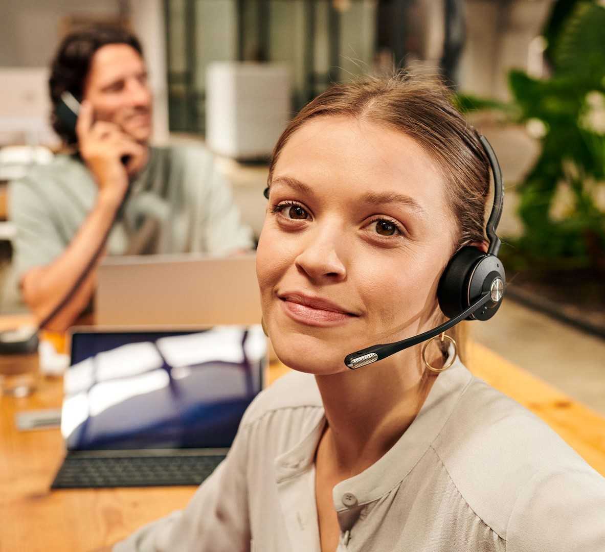 Frau im Call Center mit Headset in die Kamera schauend