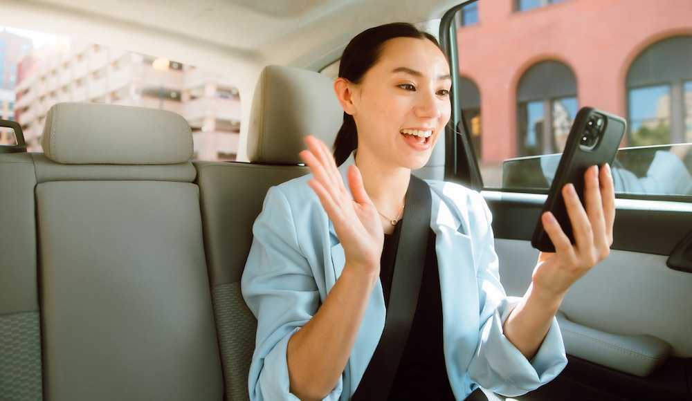 Frau auf dem Rücksitz eines Autos mit Zoom X auf ihrem Handy
