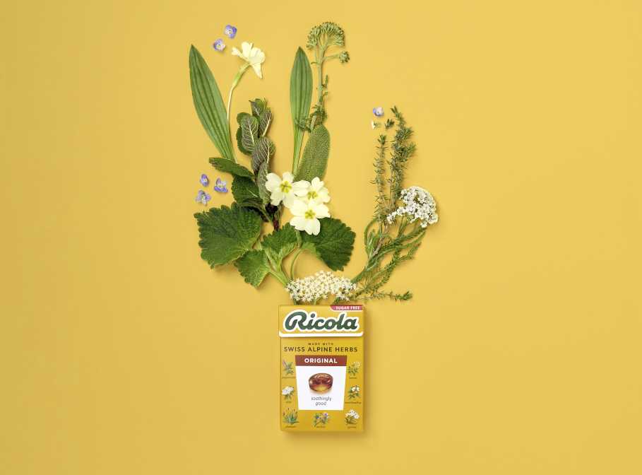 Ricola candy box surrounded by a variety of herbs